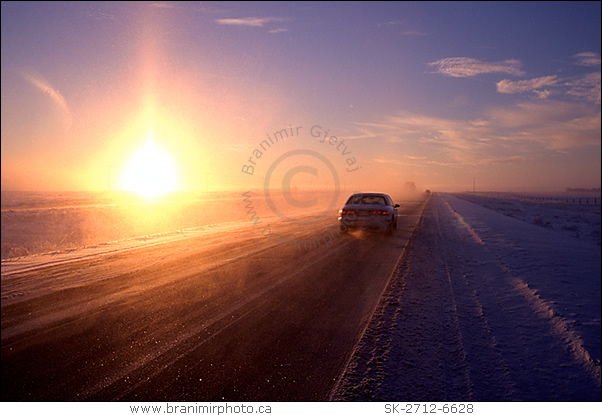 Car driving through snow storm at sunrise